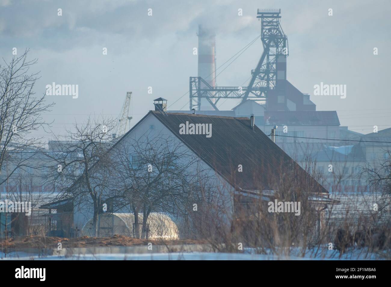 maison de village en hiver sur le fond d'une usine industrielle. Banque D'Images