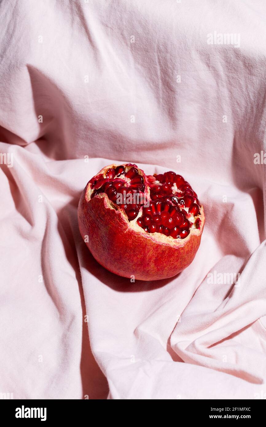 Un grenade rouge sur fond textile rose. Les fruits modernes encore la vie Banque D'Images