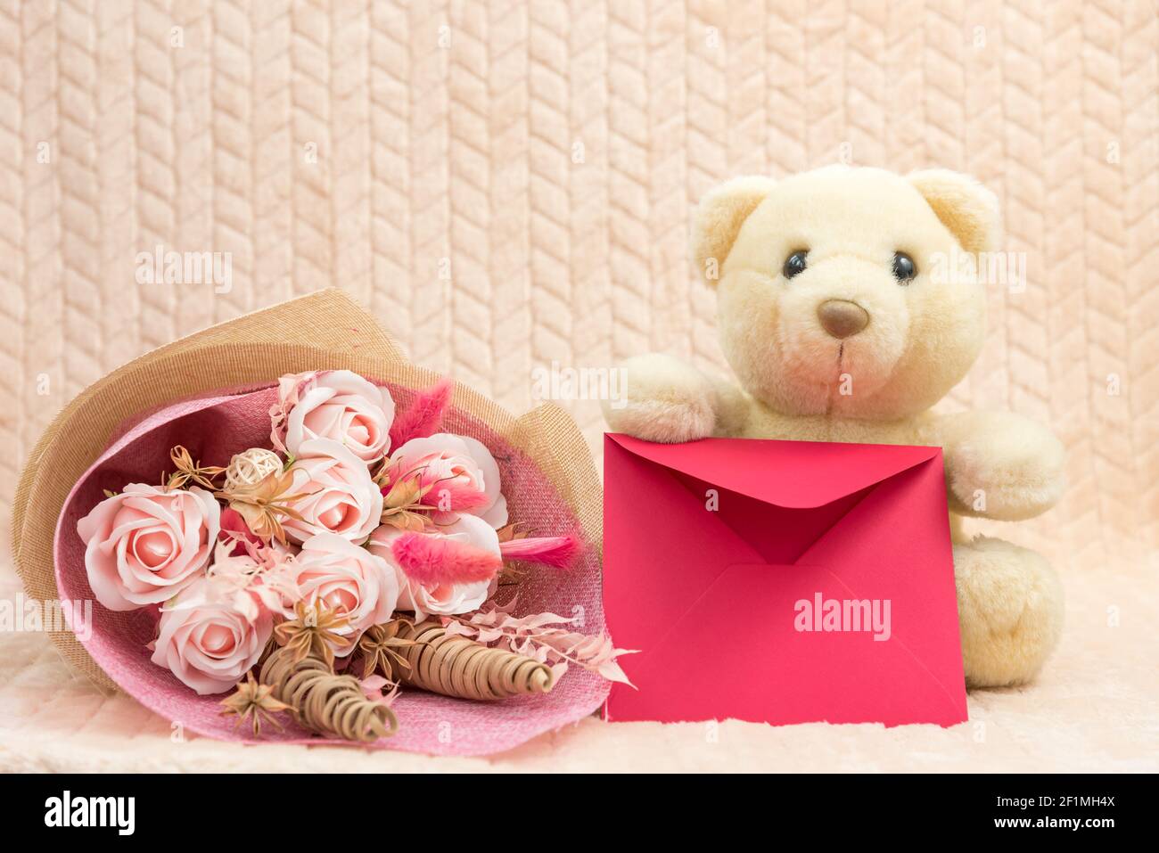 Animal en peluche ours en peluche polaire avec fleurs et enveloppe rouge avec Félicitations. Le concept de vacances pour les enfants, jour de la maman, anniversaire Banque D'Images