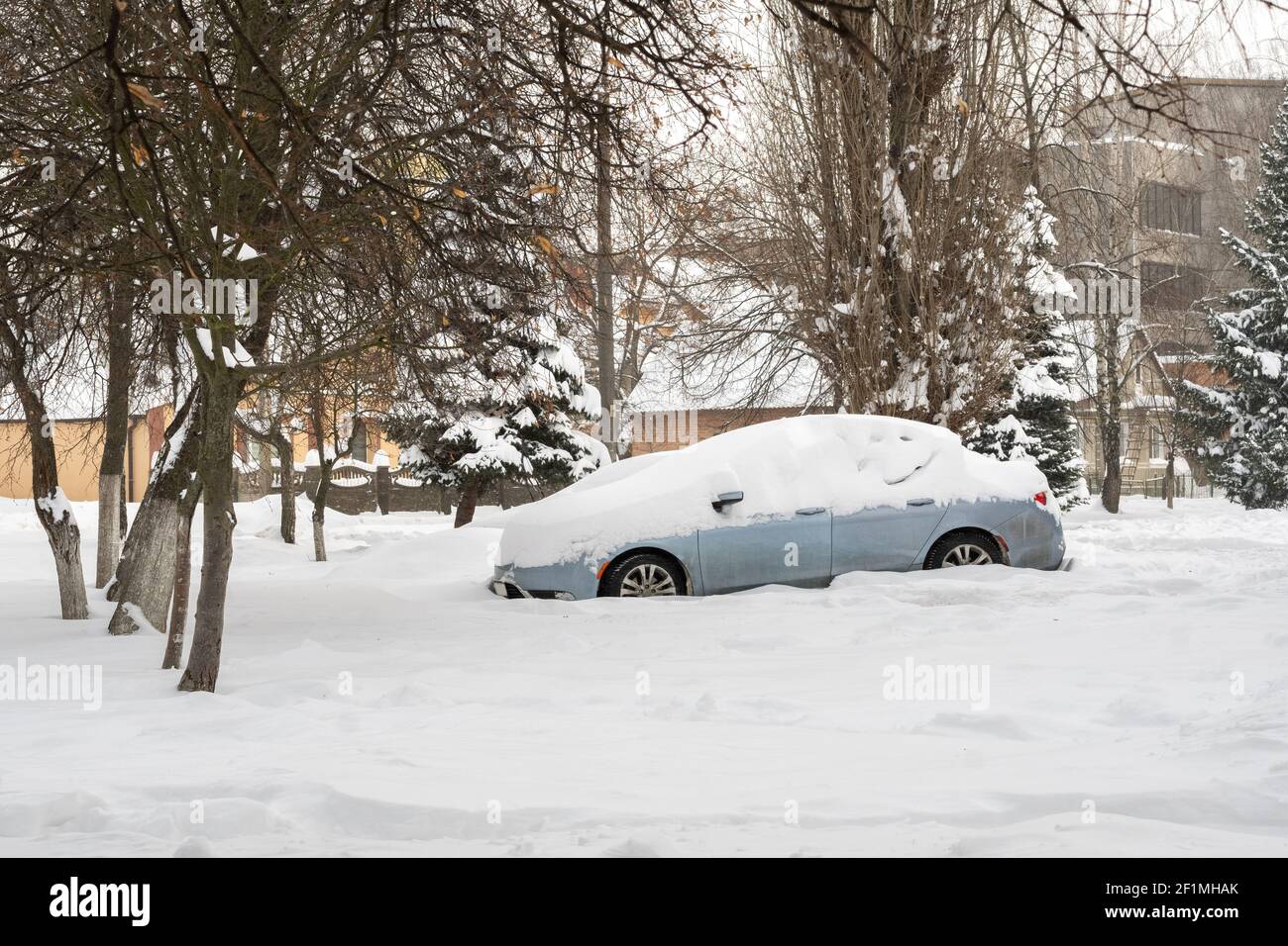 Rue de ville après blizzard. Voitures coincées sous la neige et la glace. Véhicule enterré en déneigement sur la route. Parkings en hiver après de fortes chutes de neige Banque D'Images