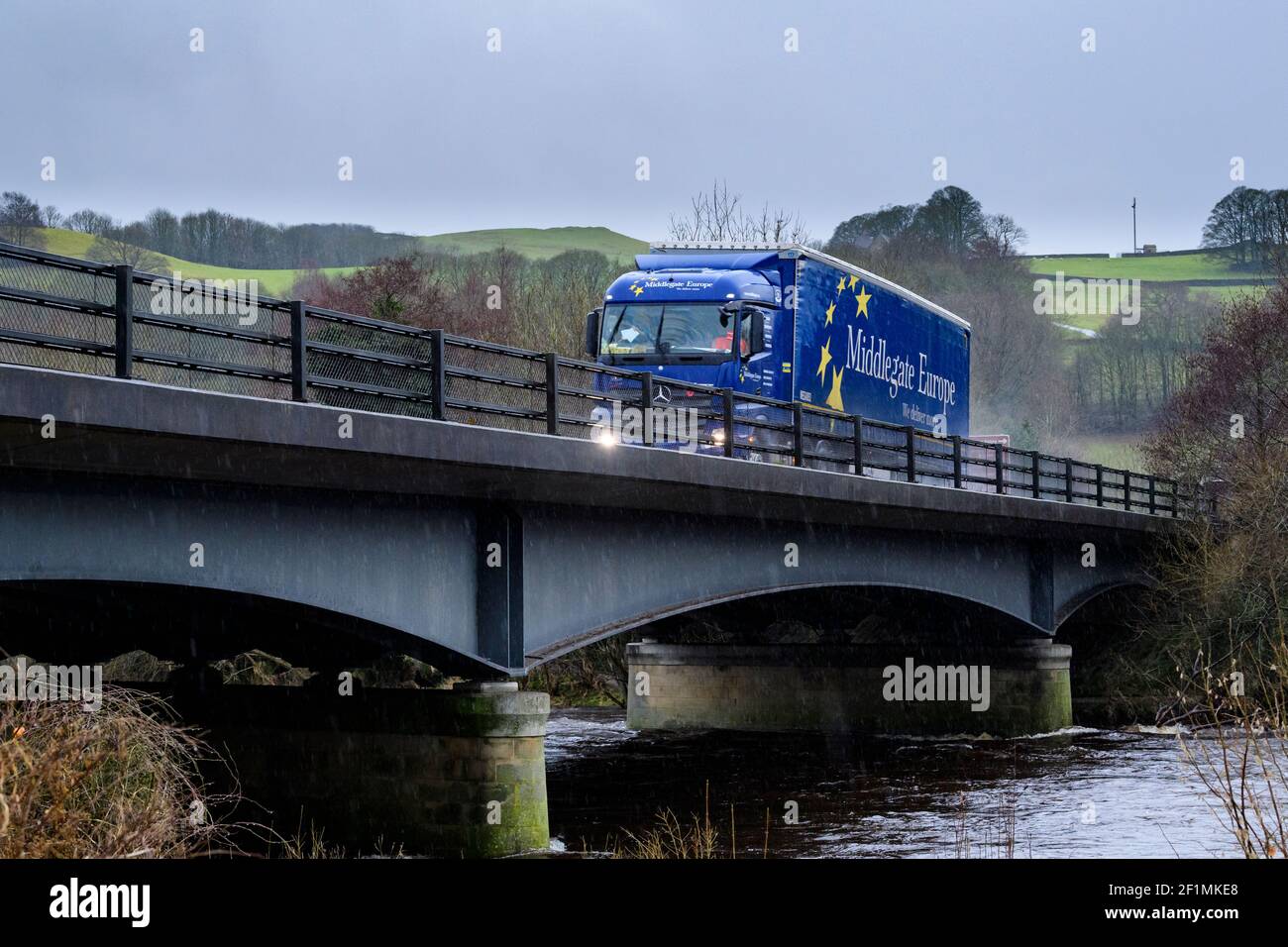 Distribution et transport par mauvais temps pluvieux (pluie) - camion (HGV) traversant le pont fluvial, pulvérisation d'eau - A59, Yorkshire, Angleterre, Royaume-Uni. Banque D'Images Distribution et transport par mauvais temps pluvieux (pluie) - camion (HGV) traversant le pont fluvial, pulvérisation d'eau - A59, Yorkshire, Angleterre, Royaume-Uni. Banque D'Images
