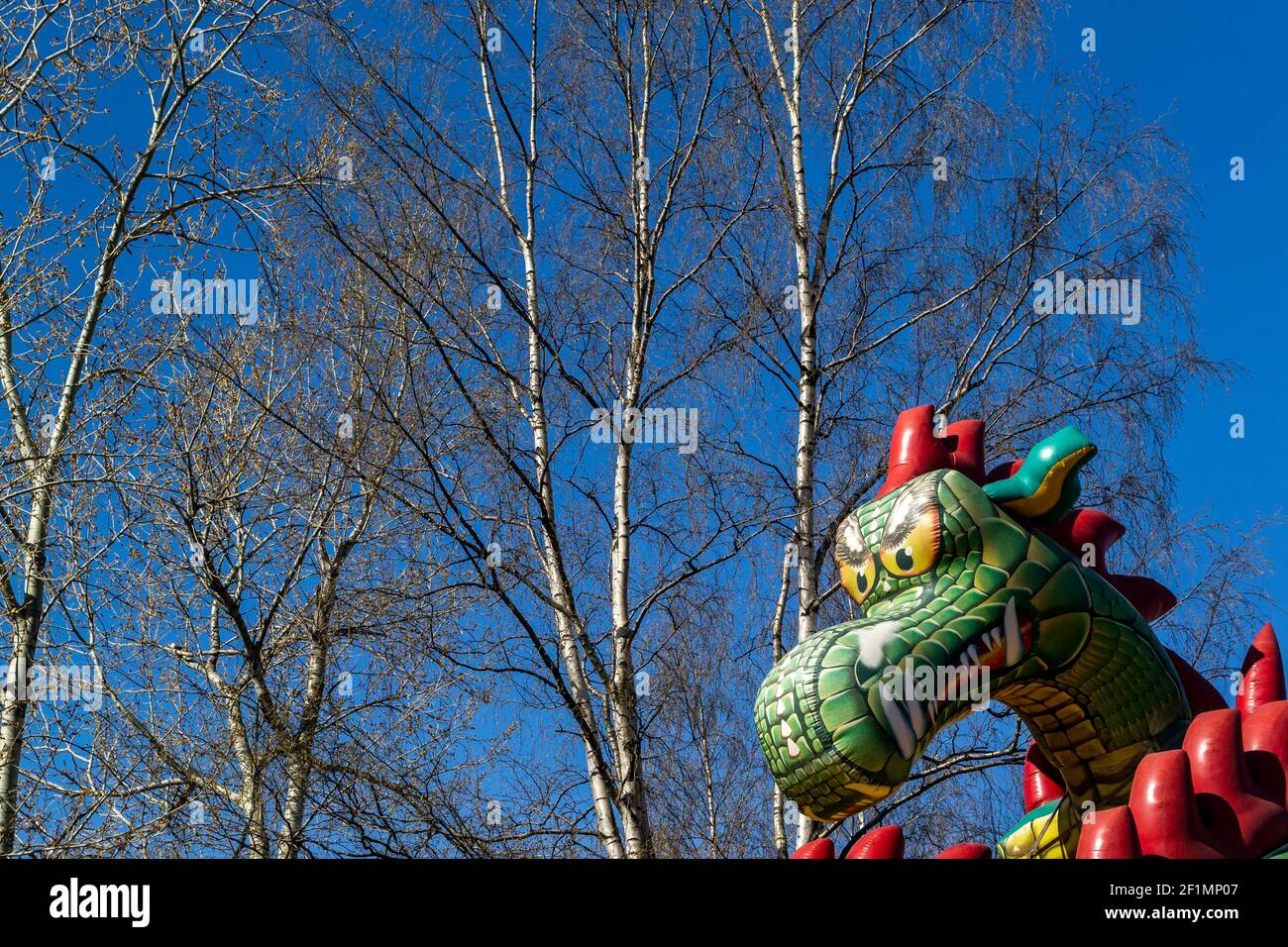 arrière-plan abstrait avec la tête d'un dragon gonflable en face bouleau et ciel bleu Banque D'Images