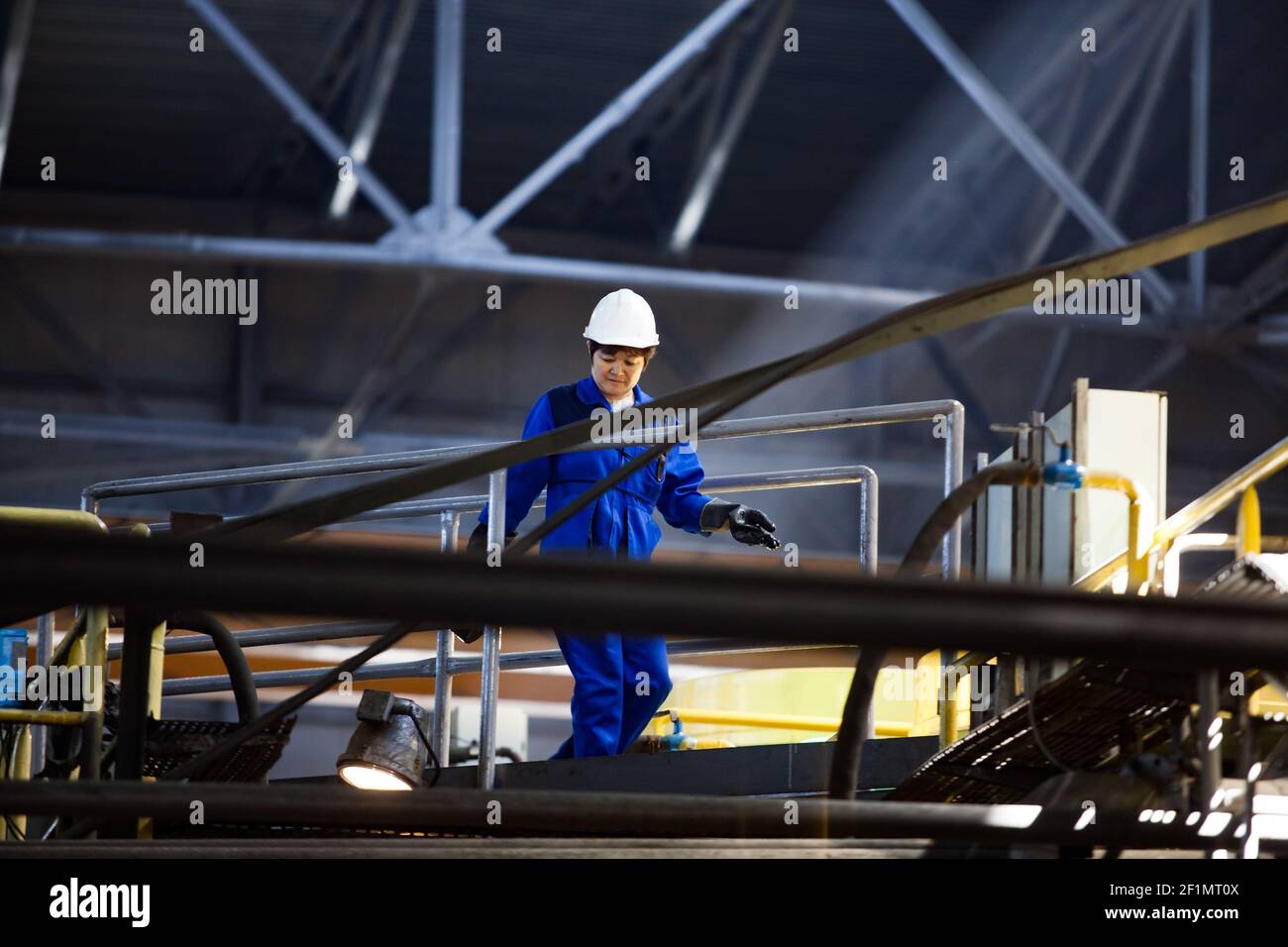 Koktau, province d'Aktobe, Kazakhstan - 06 mai 2012 : usine de concentration de minerai de cuivre. Femme ouvrière asiatique sur le fond de constructions en acier de tuyaux. Banque D'Images