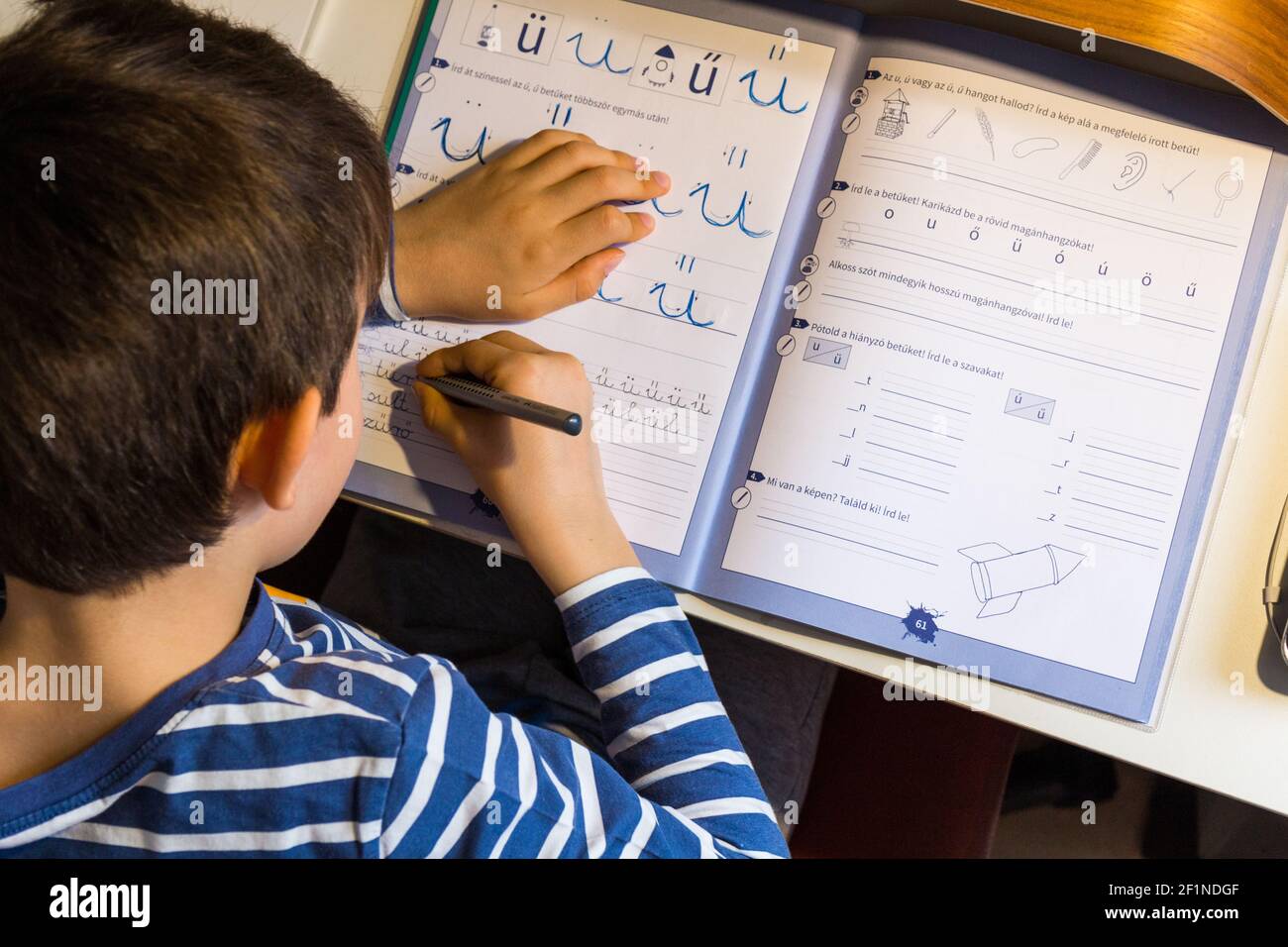 Enseignement à distance, apprentissage à la maison pendant une pandémie COVID-19. Garçon enfant écrivant des lettres vue du dessus directement d'en haut, Hongrie, Europe Banque D'Images