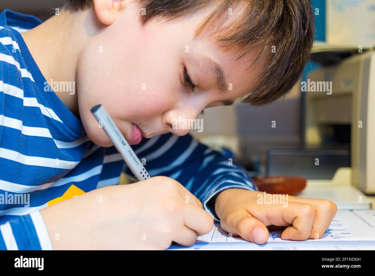 Enseignement à distance, apprentissage à la maison pendant une pandémie COVID-19. Garçon enfant écrivant des lettres avec crayon gros plan, Hongrie, Europe Banque D'Images