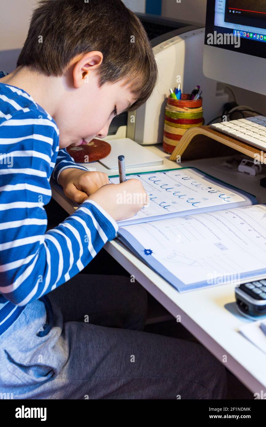 Enseignement à distance, apprentissage à la maison pendant une pandémie COVID-19. Garçon enfant écrivant des lettres devant l'ordinateur, Hongrie, Europe Banque D'Images