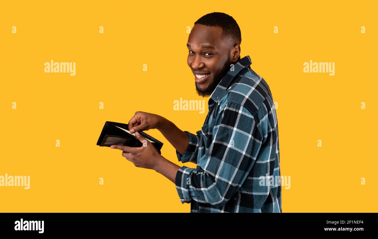 Concept de pickpocketing. Un homme afro-américain à la mode avec de l'argent comptant sur un fond de studio jaune. Vol comptant de l'argent à Wall Banque D'Images