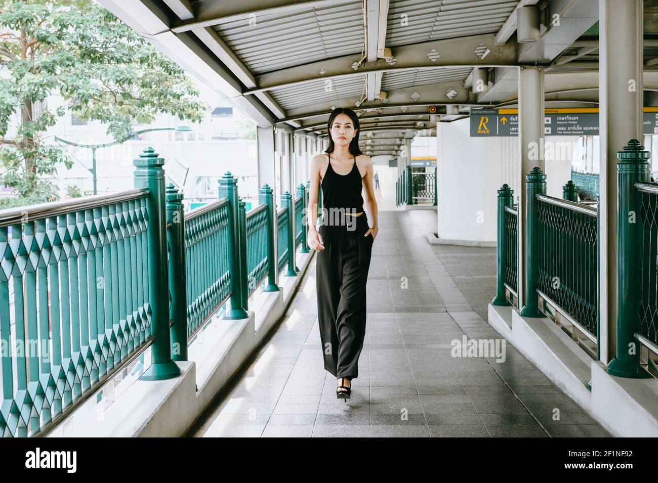 Jeune femme asiatique attrayante vêtue de noir, se dirige vers la caméra dans un élégant chemin de la ville, Bangkok Thaïlande. Banque D'Images
