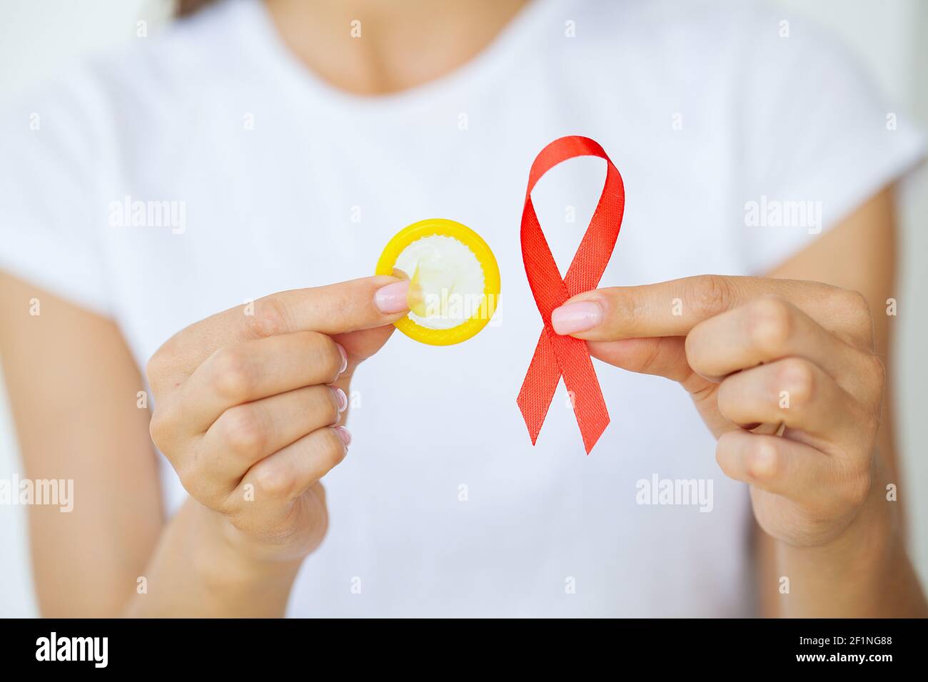 Femme d'affaires attirante avec ruban rouge et condom montrant dans les mains Banque D'Images