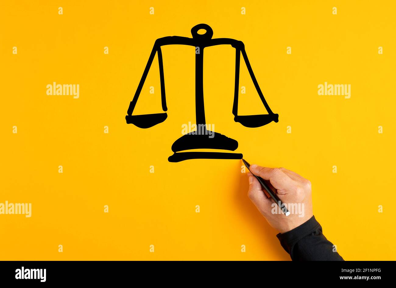 Main masculine dessinant une échelle de justice sur fond jaune. Équité, égalité ou confiance. Banque D'Images