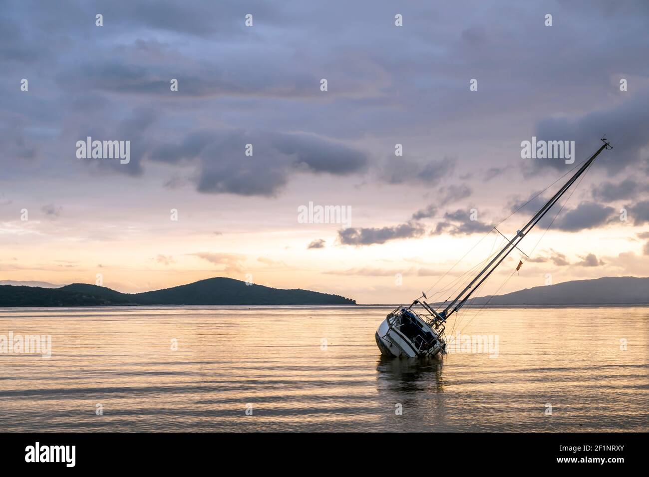 Assurance bateau et après la tempête concept: Naufrage ancré à la baie. Épave du bateau à voile sur la côte au coucher du soleil avec ciel spectaculaire et espace de copie Banque D'Images