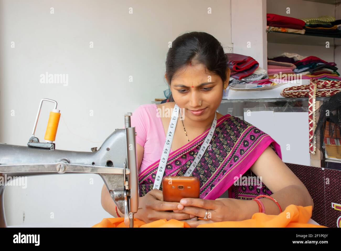 femme indienne tailleur tenant le téléphone mobile à l'atelier Banque D'Images