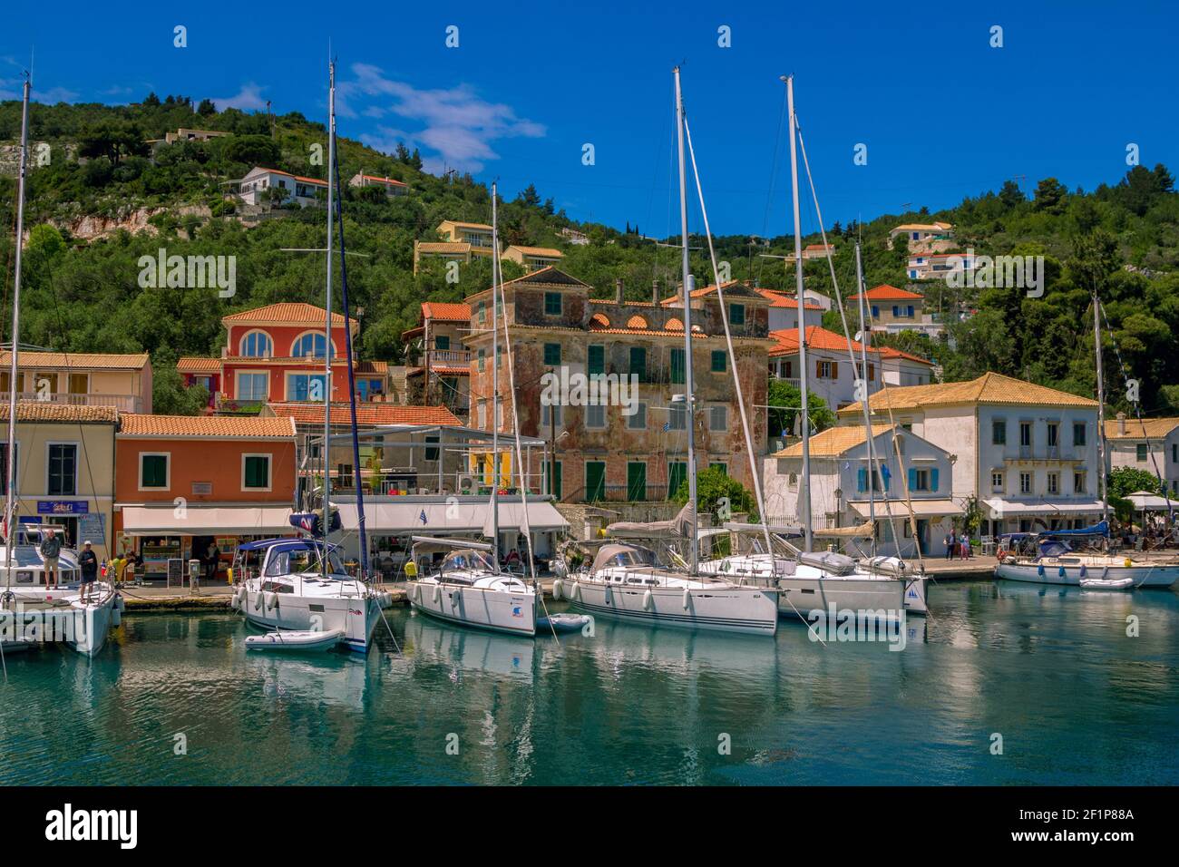 Ile de Paxos/Grèce- 7 mai 2019: Vue sur le magnifique port de Loggos - baie de mer avec l'eau turquoise calme, les navires et les yachts coloré vieilles maisons et bleu s Banque D'Images