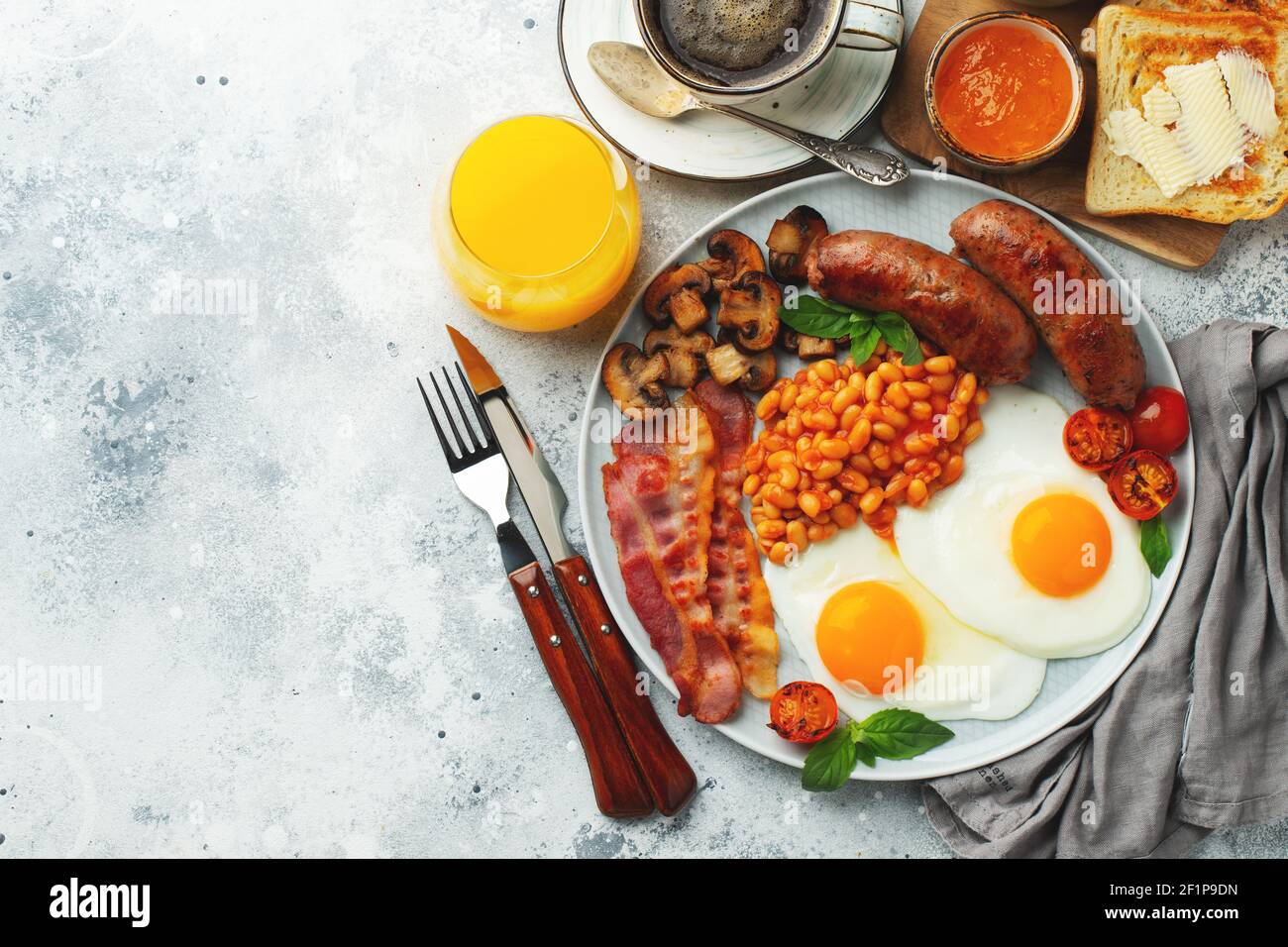 Petit déjeuner anglais complet sur une assiette avec œufs frits, saucisses, bacon, haricots