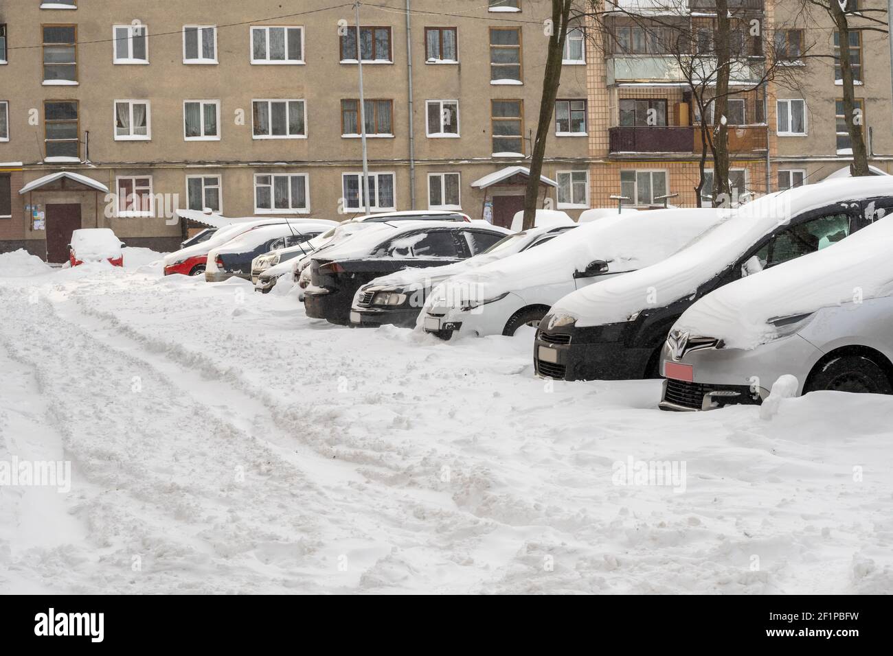 Lutsk, Ukraine - février 12,2020 : rue de la ville après blizzard. Voiture coincée dans la neige et la glace. Véhicule enterré en déneigement. Parking en hiver après Banque D'Images