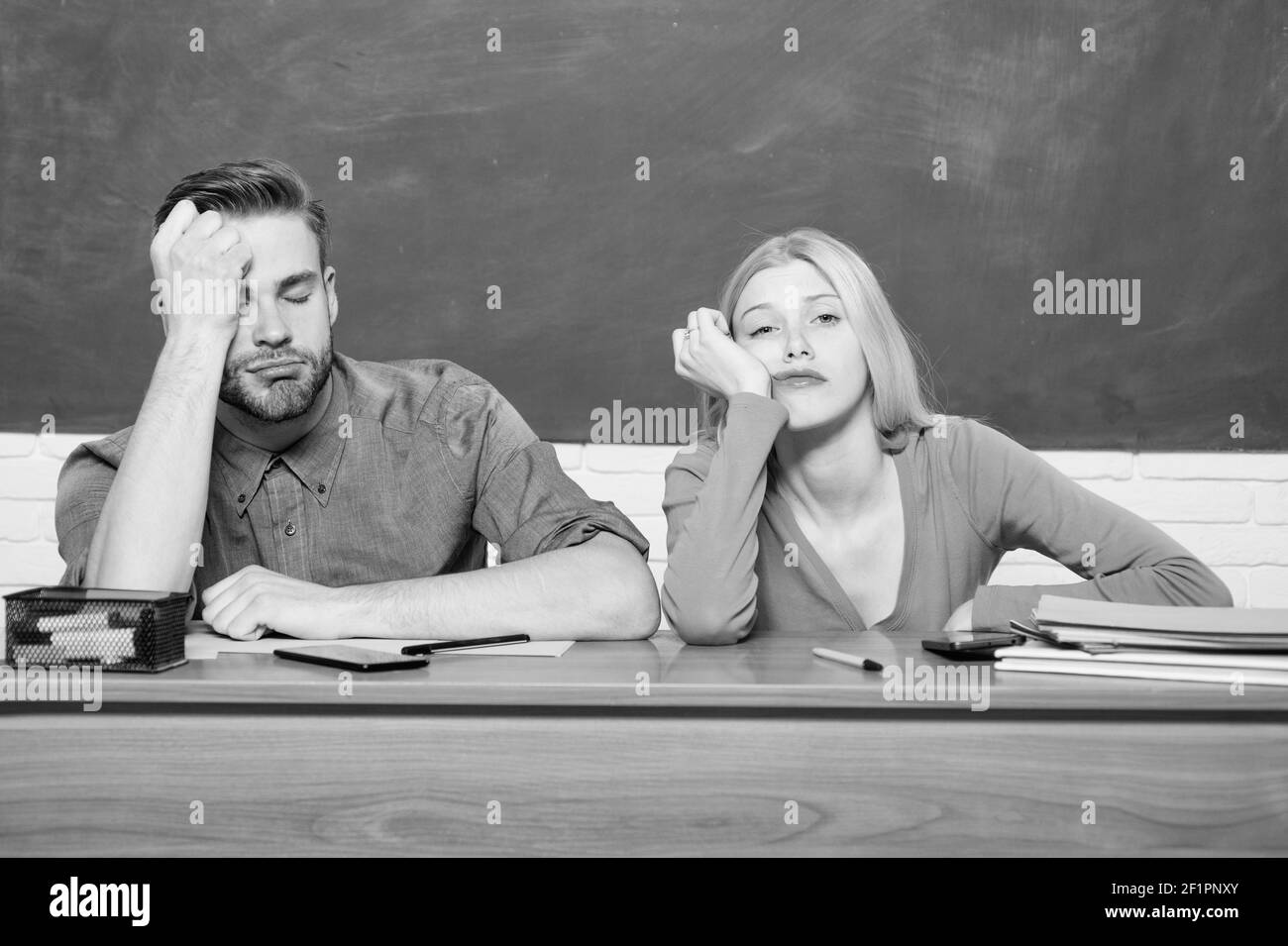 Problèmes de vie des étudiants. S'ennuyer. Étudier au collège ou à l'université. Demandez un programme gratuit. Couple amis étudiant université. Guy et la fille fatiguée ou étudiant paresseux se penchent sur le bureau dans la salle de classe. Banque D'Images