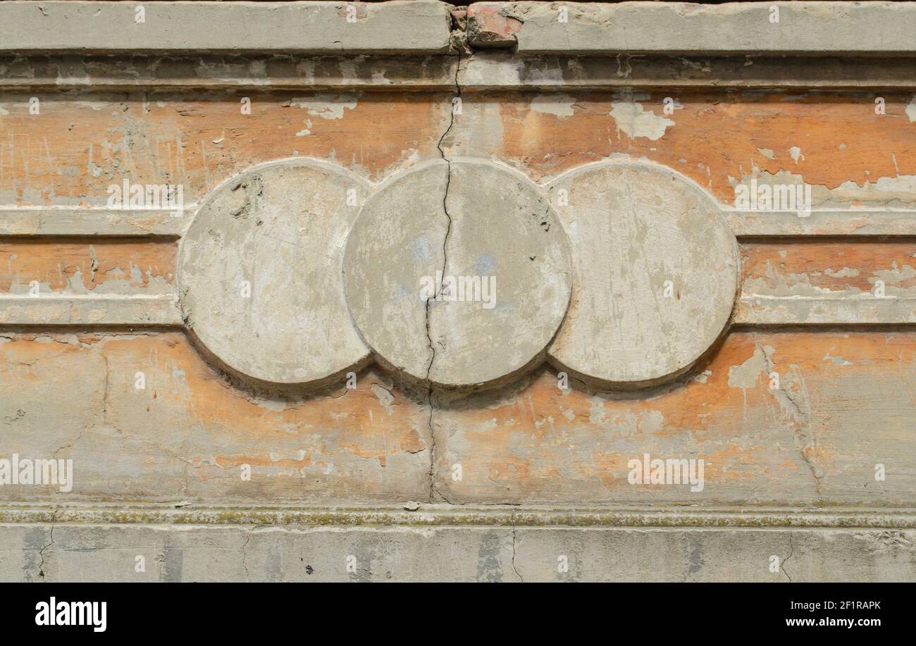 Façade en béton fissuré. Trois cercles de stuc moulés sur la façade beige du bâtiment avec une fissure. Arrière-plan architectural pour Banque D'Images