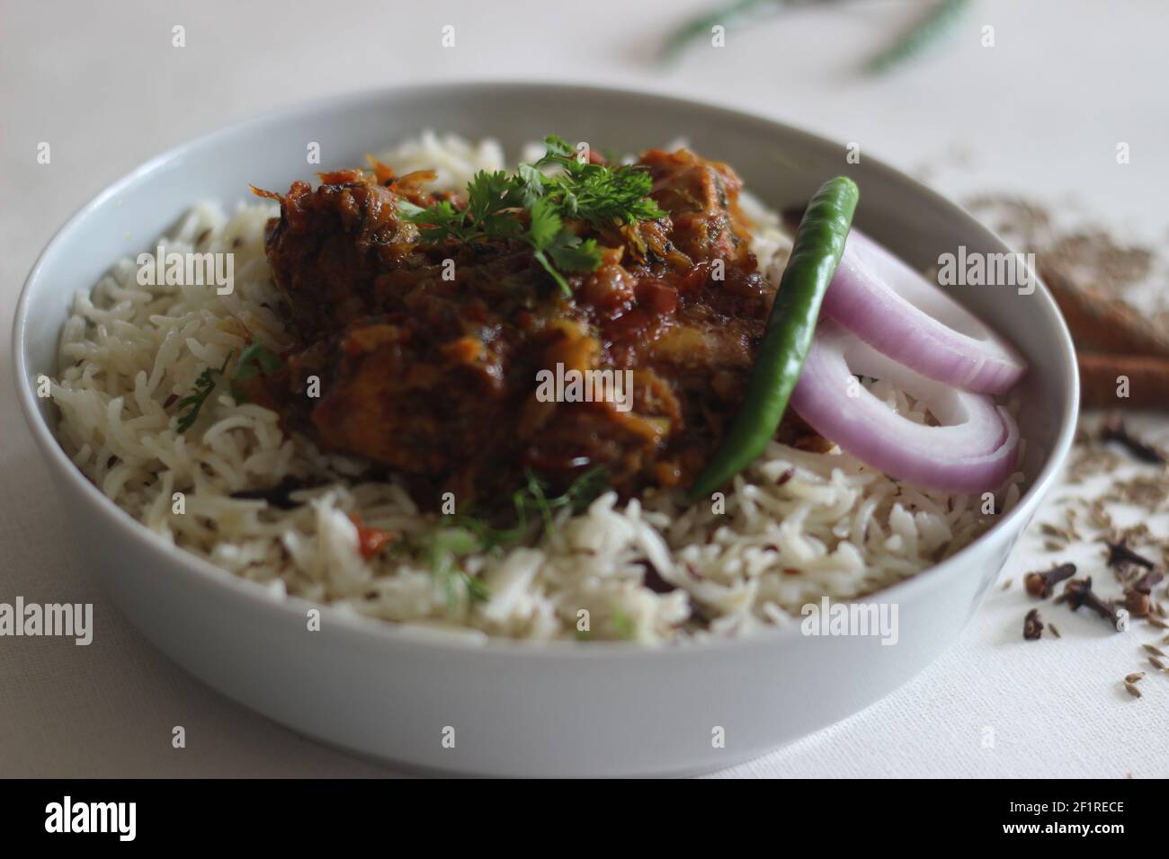 Riz Jeera et poulet rôti à sec. Une préparation de riz simple et savoureuse en une casserole avec des ingrédients de base. Prise sur fond blanc Banque D'Images