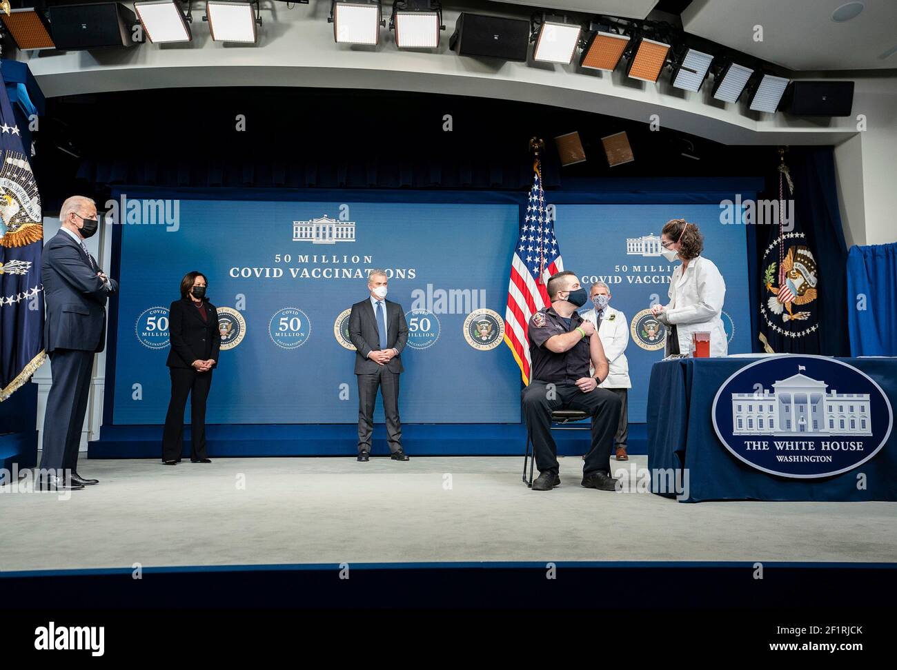 Le président américain Joe Biden, Le vice-président Kamala Harris Maison Blanche COVID-19 Coordinateur de réponse Jeff Zients et le conseiller médical en chef du Président Anthony Fauci regarde DC Firefighter et EMT Corey Hamilton se prépare à recevoir son vaccin COVID-19 lors d'un événement célébrant le 50 millionième vaccin COVID-19 au Bureau exécutif d'Eisenhower Bâtiment le 25 février 2021 à Washington, D.C. Banque D'Images