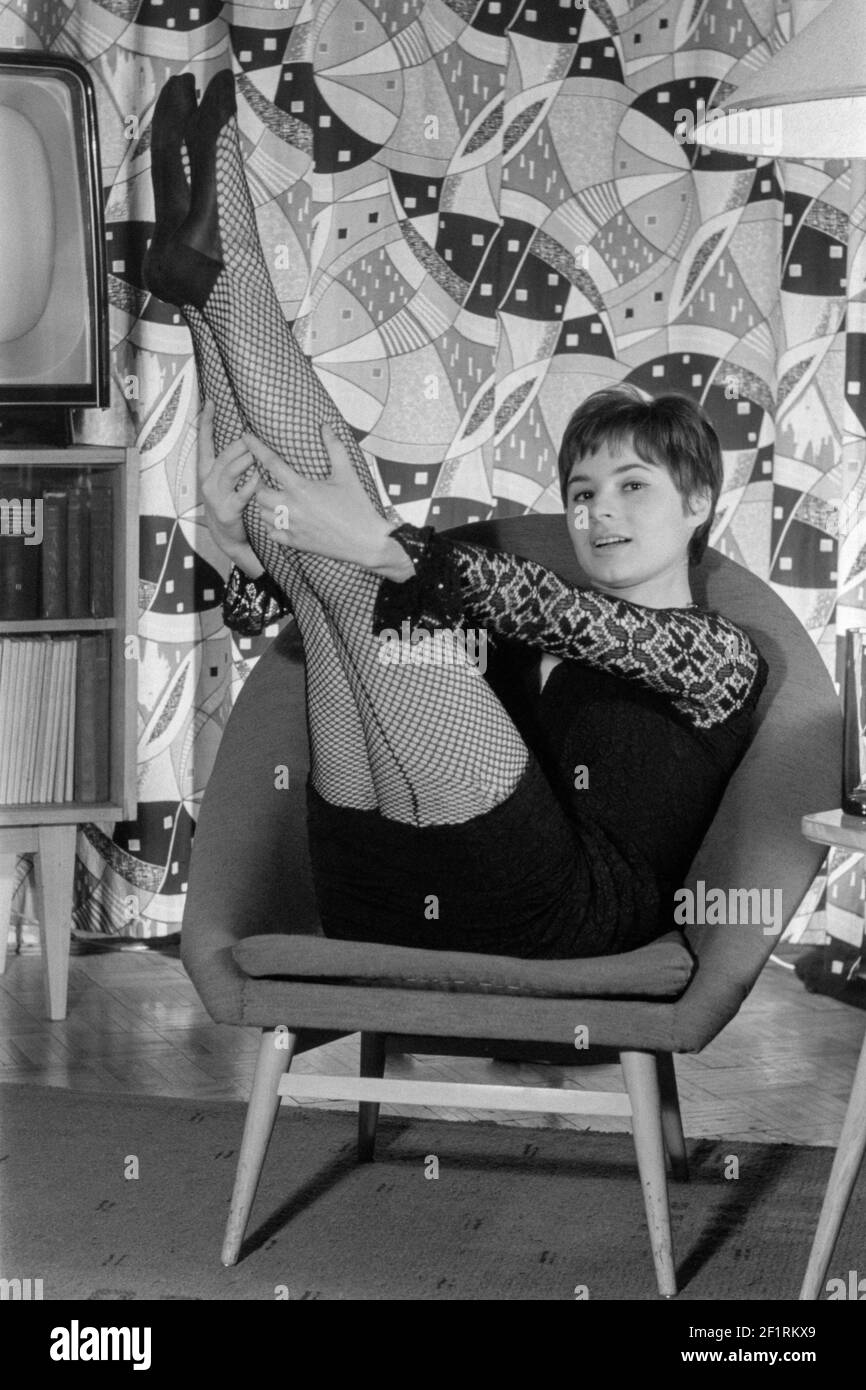jeune femme aux cheveux courts portant des bas de résille et mini habillez-vous dans une chaise vintage à la maison années 1970 hongrie Banque D'Images