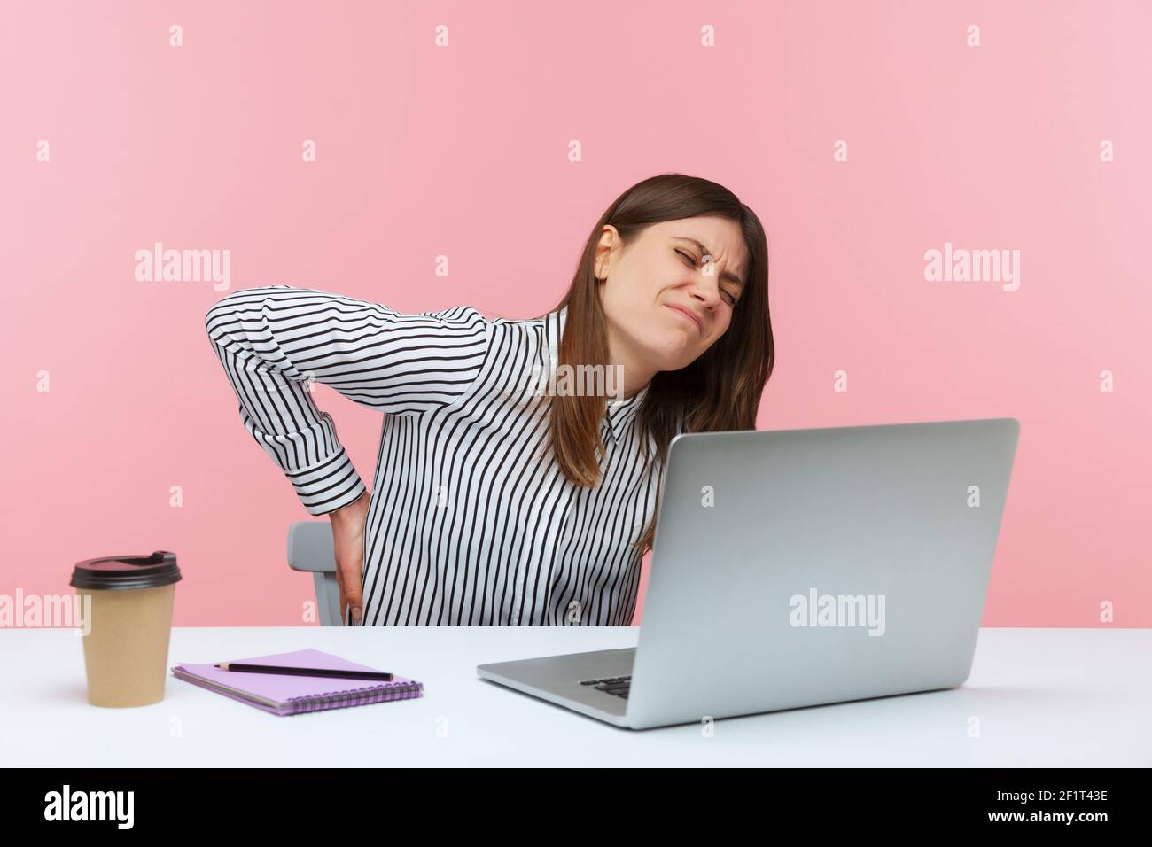 Mécontent insatisfait employée de bureau touchant et massant la colonne vertébrale assis au travail, se sentant mal dans le bas du dos, a des problèmes avec les reins. IND Banque D'Images