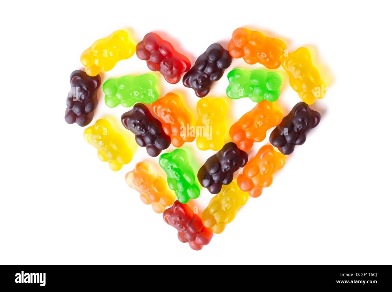 Bonbons à l'ours en gelée multicolores disposés en forme de cœur sur fond blanc. Banque D'Images