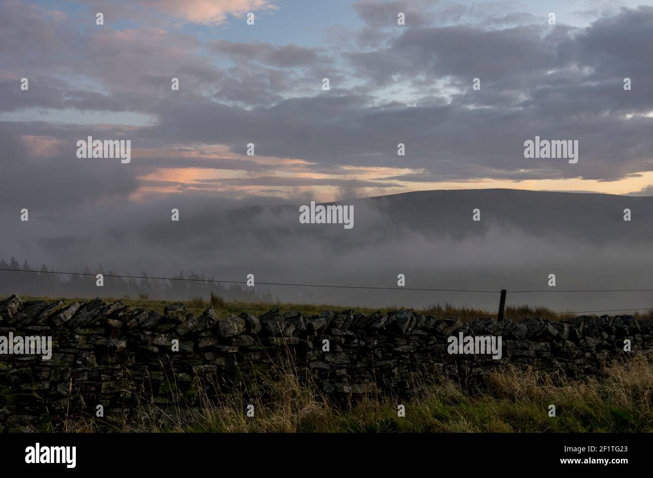 Un mur en pierre sèche dans les Pennines du Nord, comté de Durham, avec une brume d'automne basse dans le fond enveloppant les collines derrière Banque D'Images