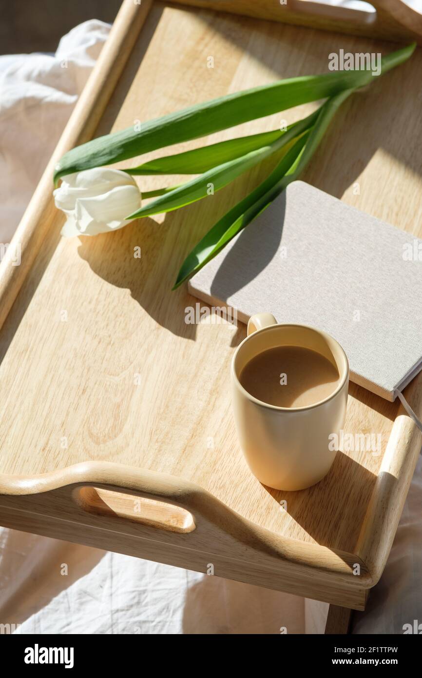 Plateau petit déjeuner en bois avec tasse de café, fleurs de tulipe, journal sur le lit. Romantique, concept d'amour. Banque D'Images Plateau petit déjeuner en bois avec tasse de café, fleurs de tulipe, journal sur le lit. Romantique, concept d'amour. Banque D'Images