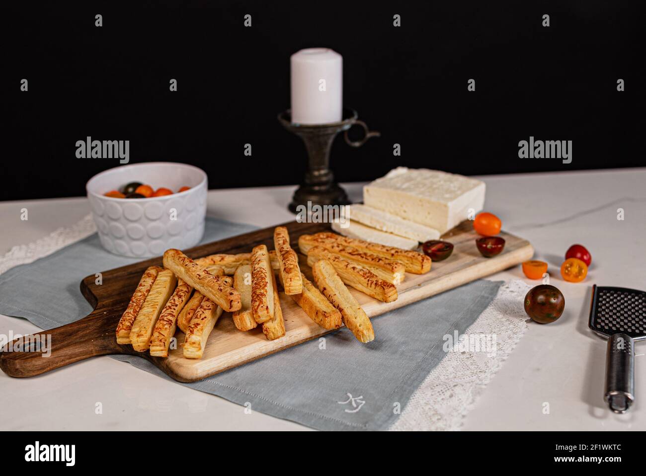 Une pile de bâtonnets de pain salé sur une coupe de bois embarquez avec du fromage et des tomates Banque D'Images