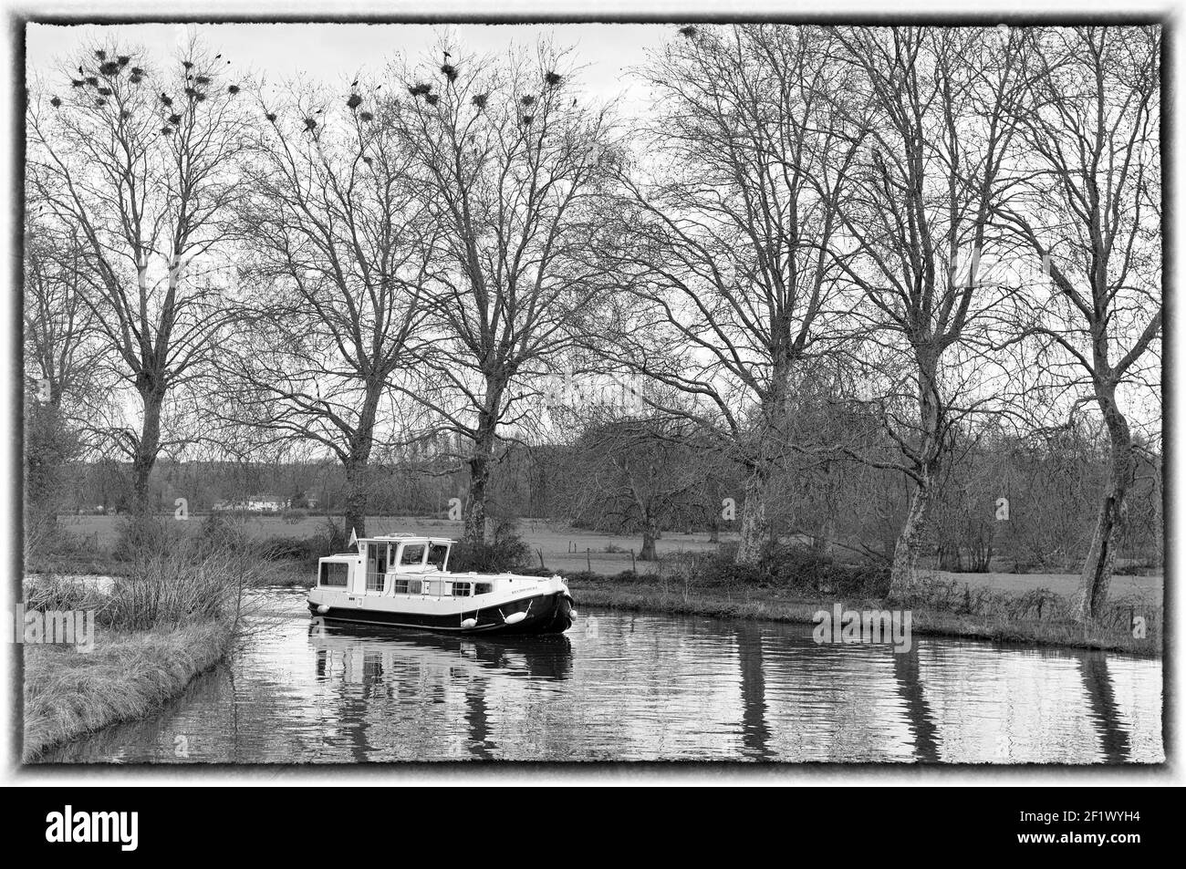 Bateau-canal arrondissant une courbe sur le canal du Nivernais (noir et blanc), Bourgogne, France Banque D'Images