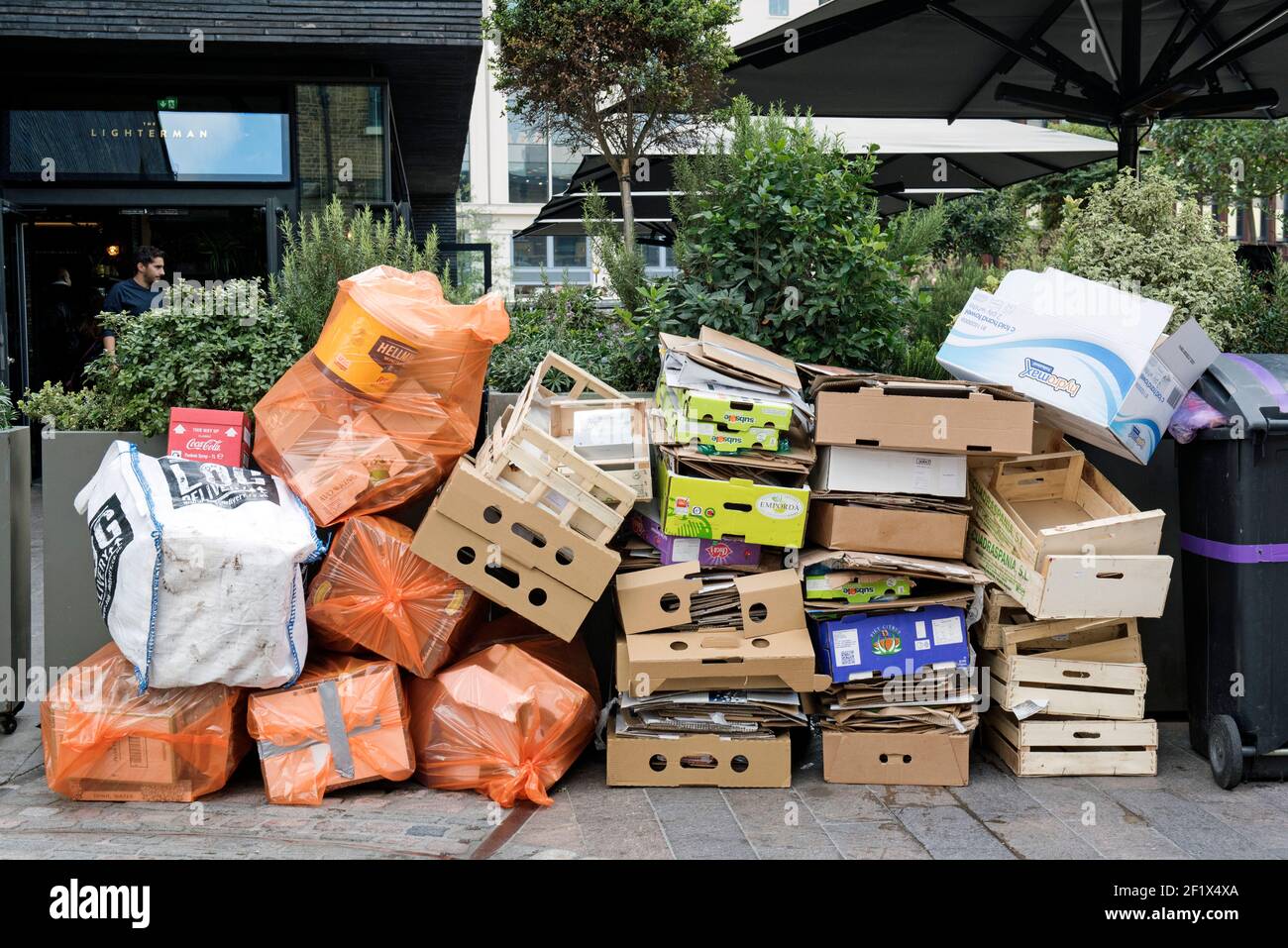 Pile de déchets, y compris carton et boîtes de fruits en bois empilées Devant le Lighterman Restaurant Granary Square, qui attend la collection Kings Croix Banque D'Images