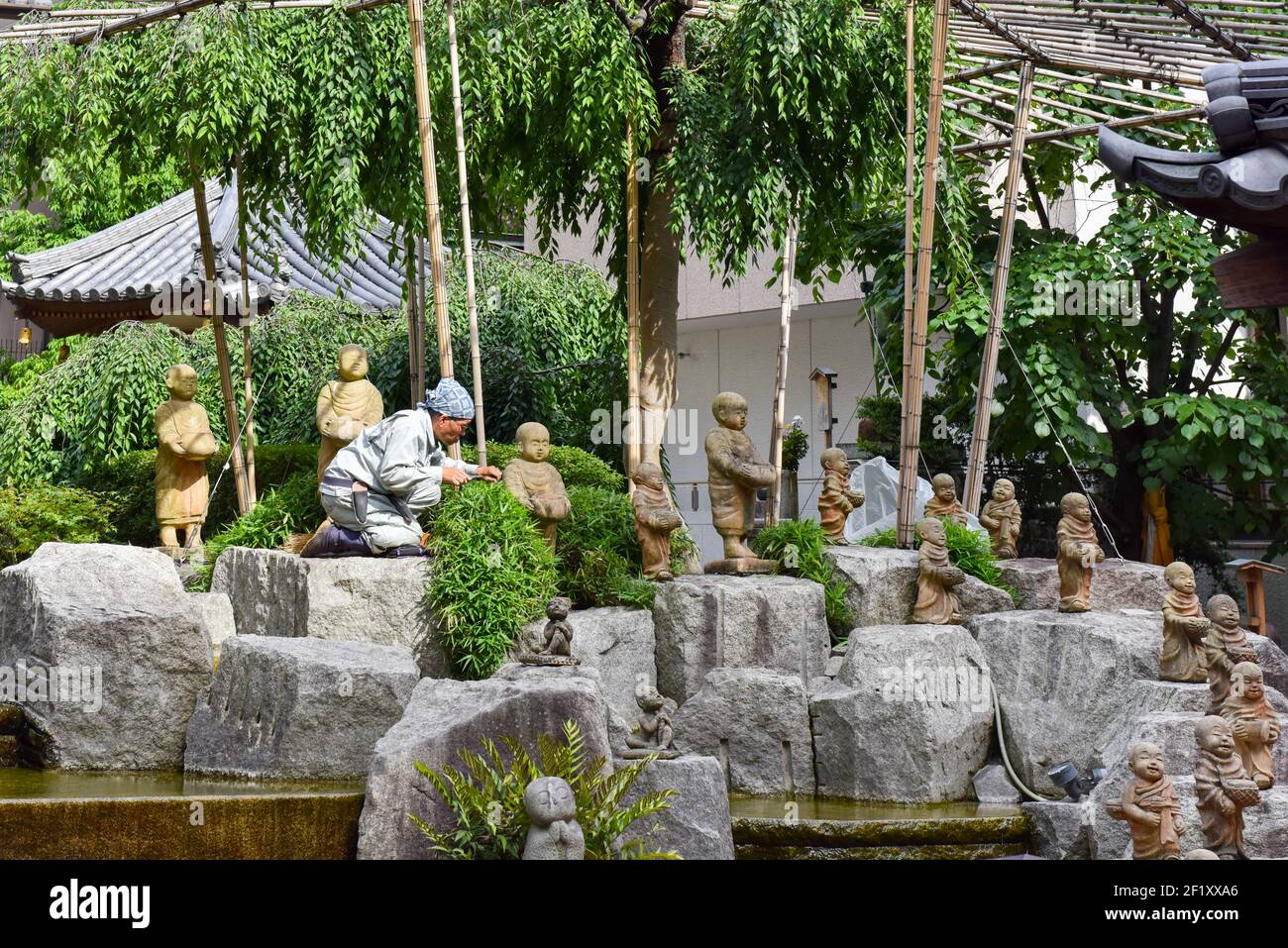 Jardinier se rendant dans une cour pleine de statues religieuses dans un sanctuaire, Kyoto Japon Banque D'Images