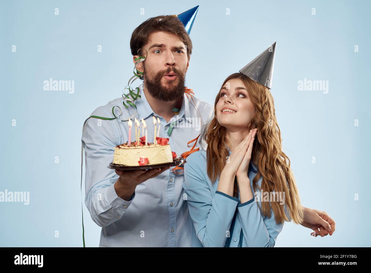 Homme Et Femme Fetent Leur Anniversaire Avec Un Gateau Et Des Chapeaux Sur Fond Bleu Photo Stock Alamy