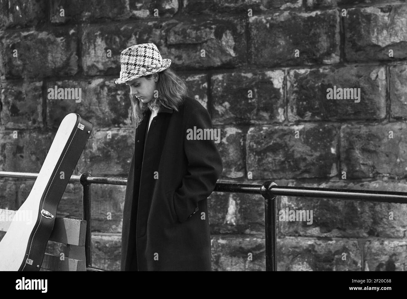 Portrait noir et blanc d'un musicien debout à côté d'un garde-corps qui regarde vers l'avenir. Banque D'Images