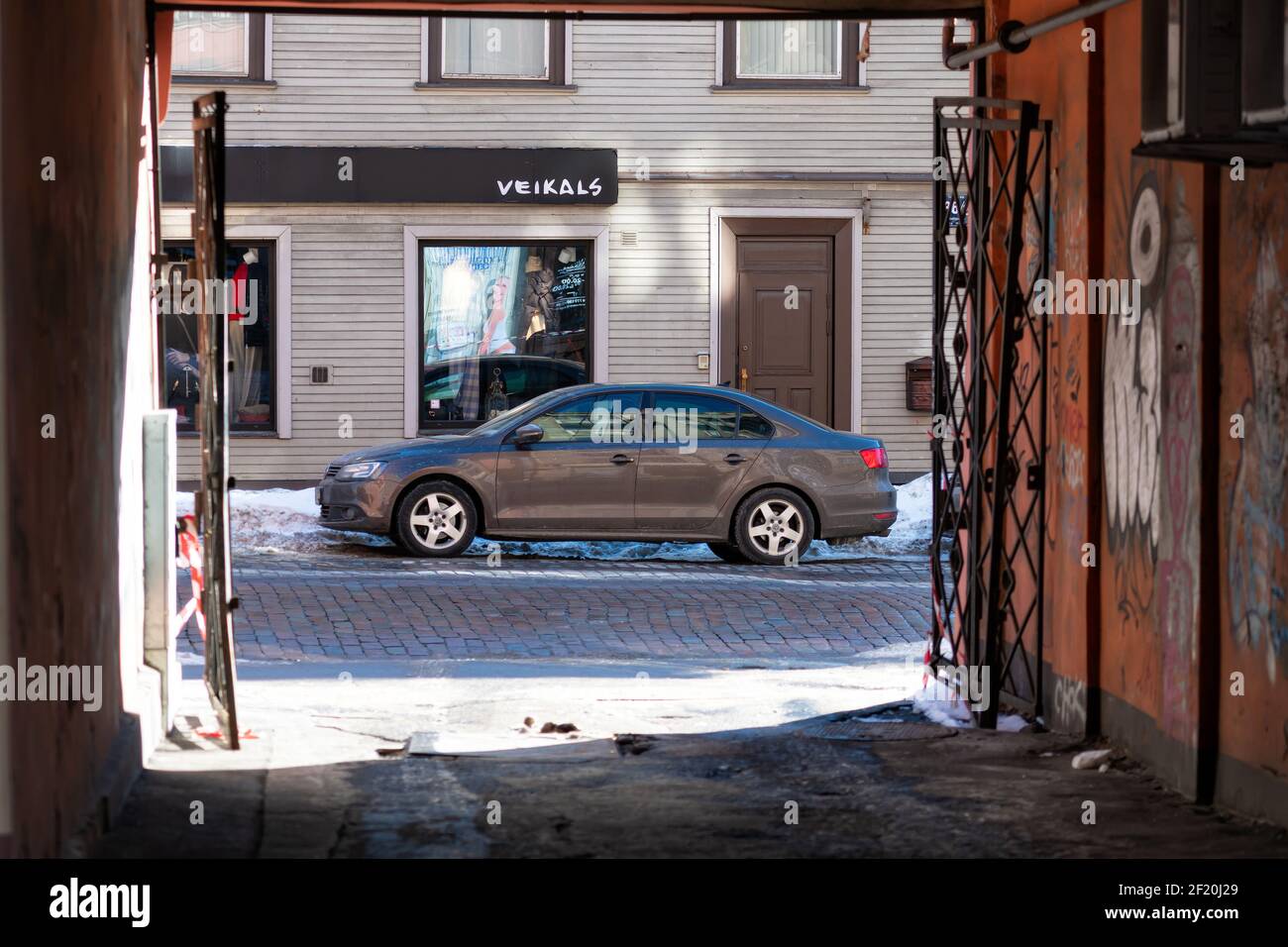 Riga, Lettonie - 17 février 2021 : vue à travers une porte vers une voiture brillante garée sur le côté de la rue Banque D'Images