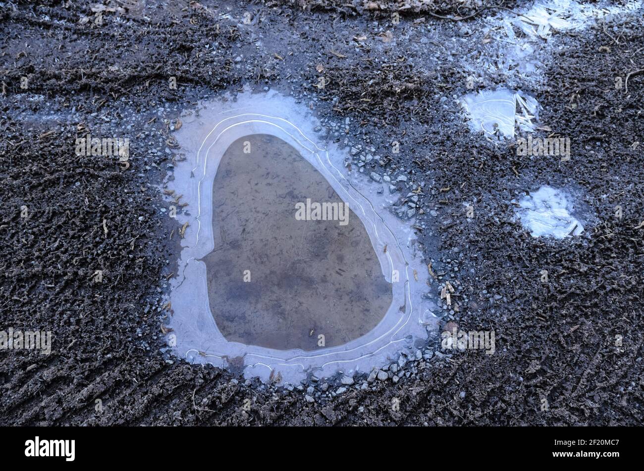 Eau gelée dans une flaque sur le sol avec structures abstraites et la surface, vue de directement au-dessus Banque D'Images