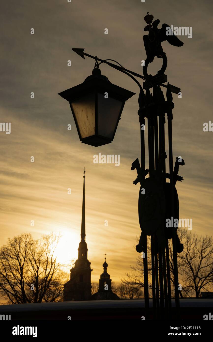 Lanterne ancienne avec une flèche et la silhouette de la cathédrale Pierre et Paul au coucher du soleil (St. Petersburg, Russie) Banque D'Images