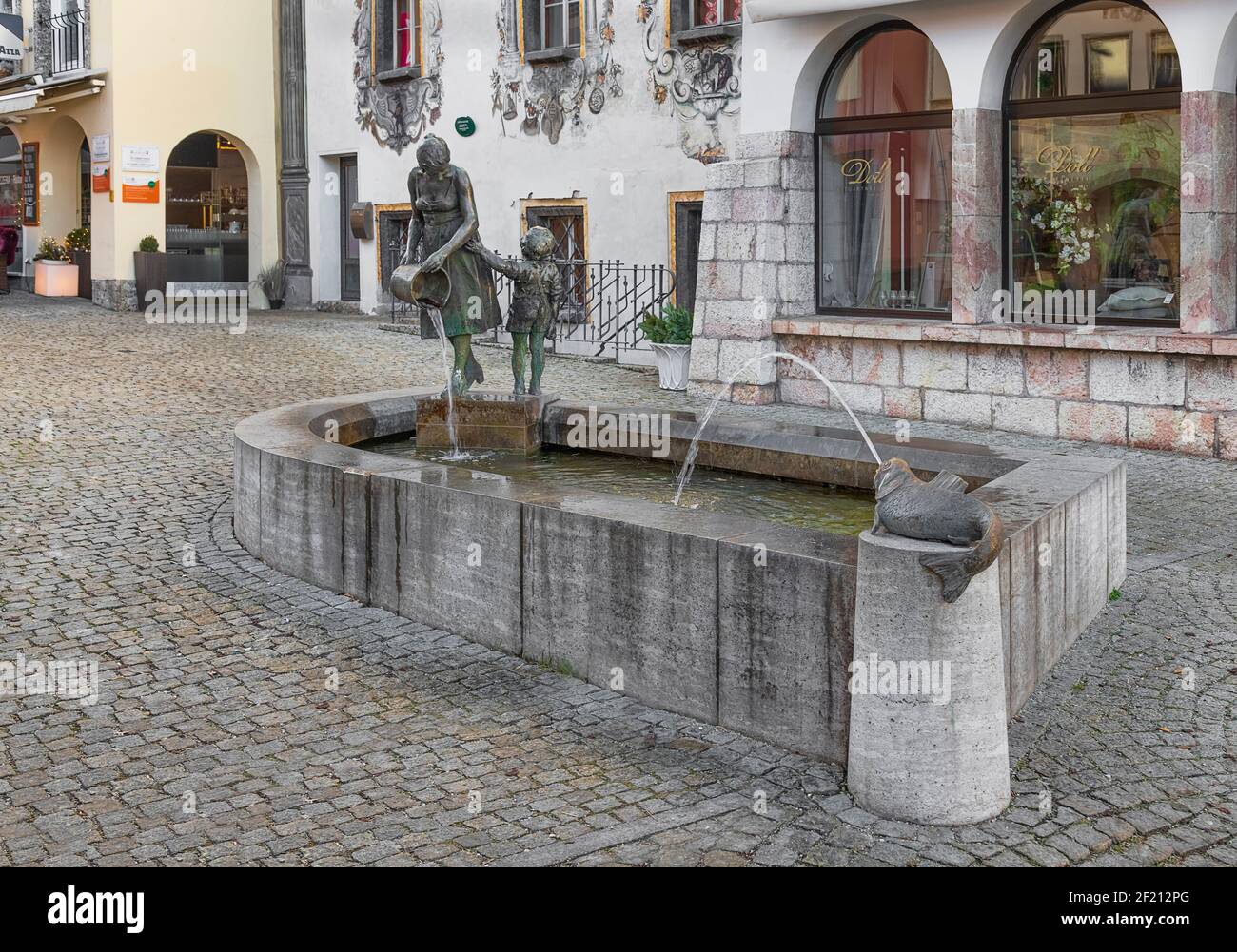 Allemagne, Bavière, Berchtesgaden, Fontaine mère et enfant également connue sous le nom de Fontaine de seau avec la façade singe de la Maison des cerfs en arrière-plan. Banque D'Images