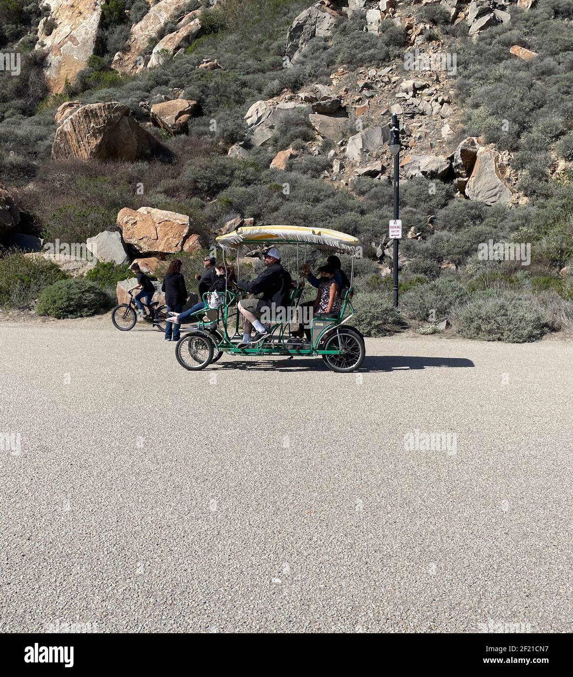 FRESNO, ÉTATS-UNIS - 28 févr. 2021: Une photo d'une famille dans un chariot vert à quatre roues de pédalos portant des masques faciaux pendant COVID en mars 2021 à l'été Banque D'Images
