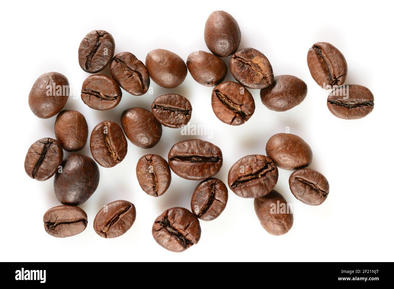 Grains de café. Quelques grains de café torréfiés durs, macro gros plan, isolés sur fond blanc. Banque D'Images