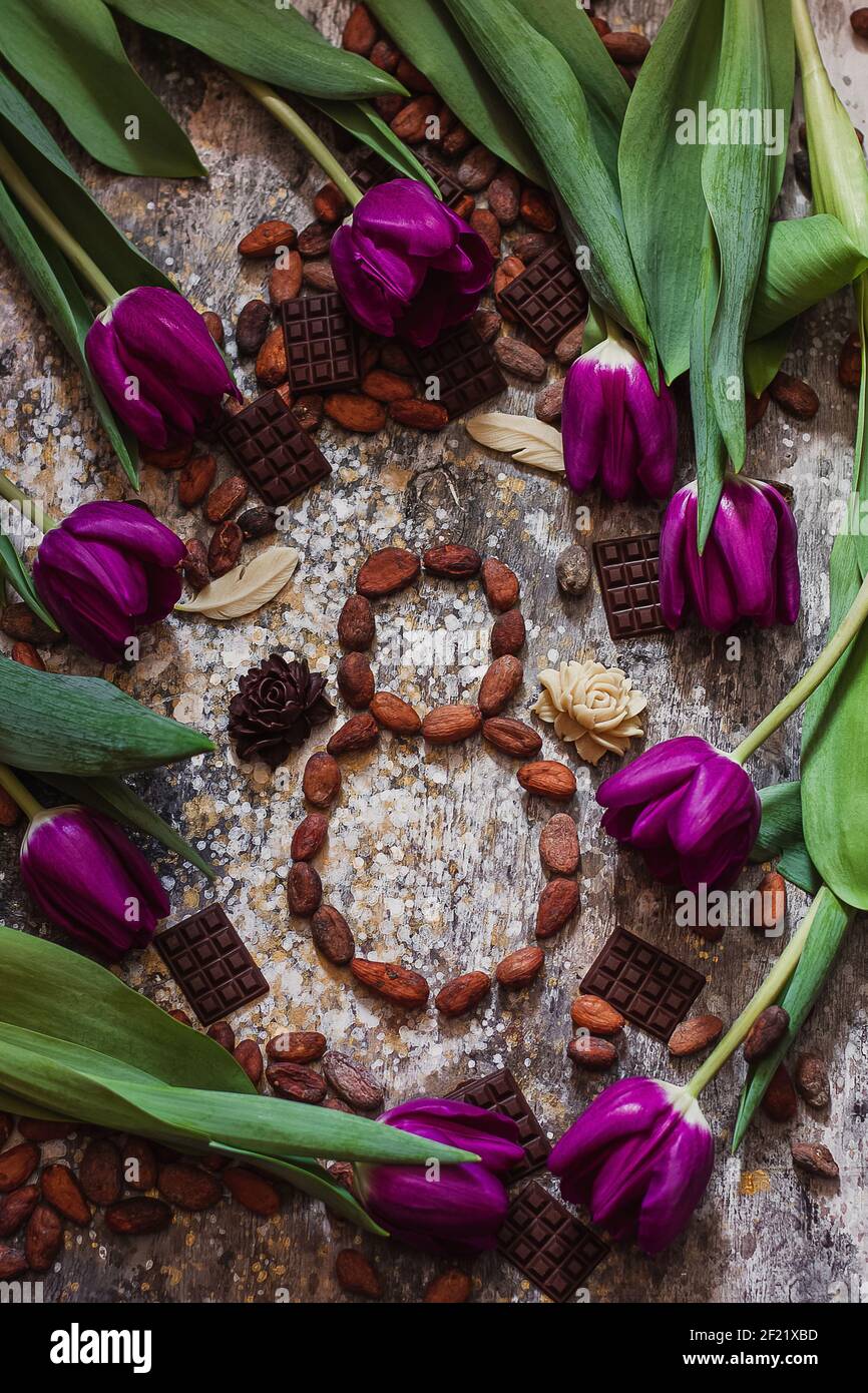 8 mars, journée internationale de la femme, huit de fèves de cacao avec des tulipes pourpres et des chocolats faits à la main autour Banque D'Images