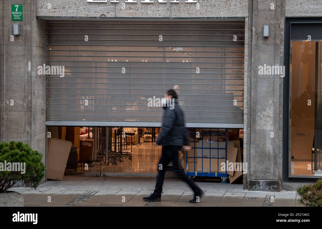 Munich, Allemagne. 10 mars 2021. Un homme passe devant un magasin de détail du centre-ville avec une porte à demi-fermeture à enroulement qui est mise en place. Credit: Peter Kneffel/dpa/Alay Live News Banque D'Images