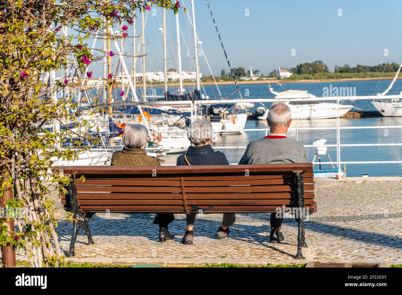 Trois personnes âgées se détendent sur la plage en regardant la marina Sur la frontière Portugal - Espagne Banque D'Images