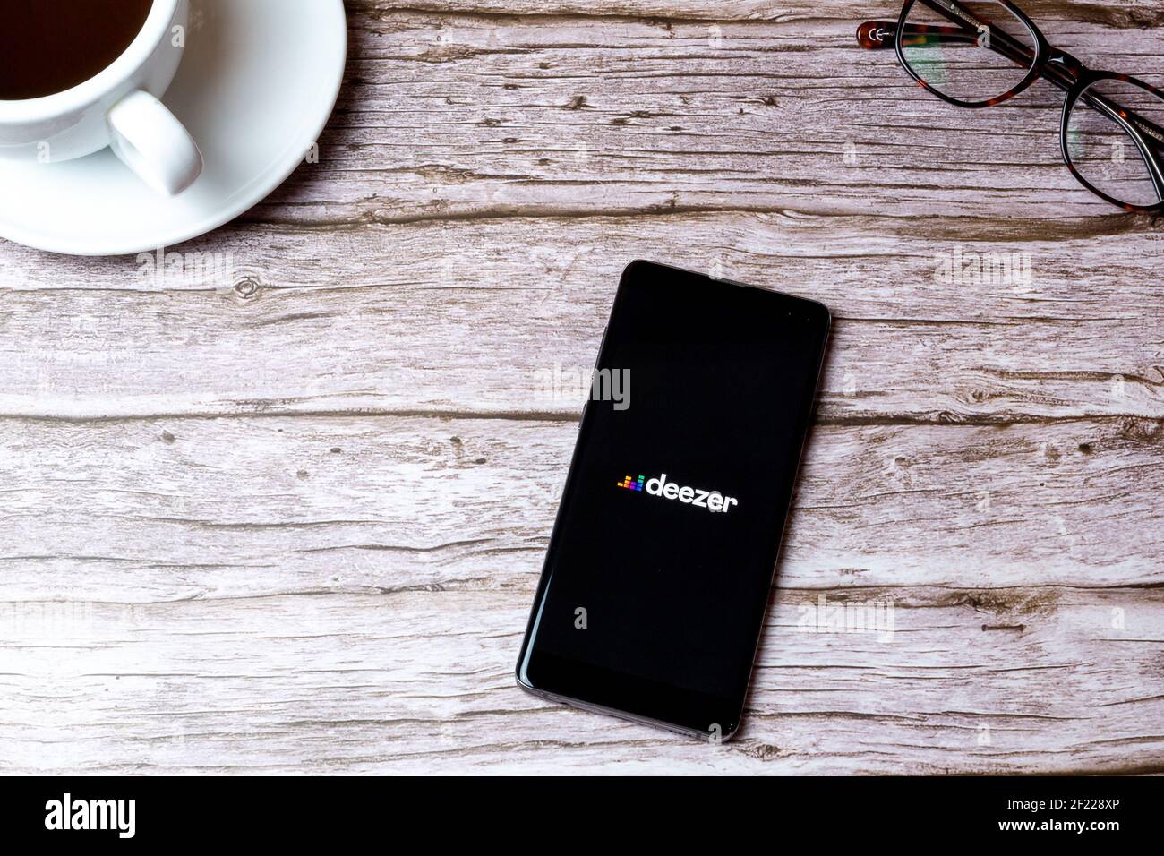 Un téléphone portable ou mobile posé sur un bois Table ou bureau avec l'application Deezer Music ouverte Banque D'Images