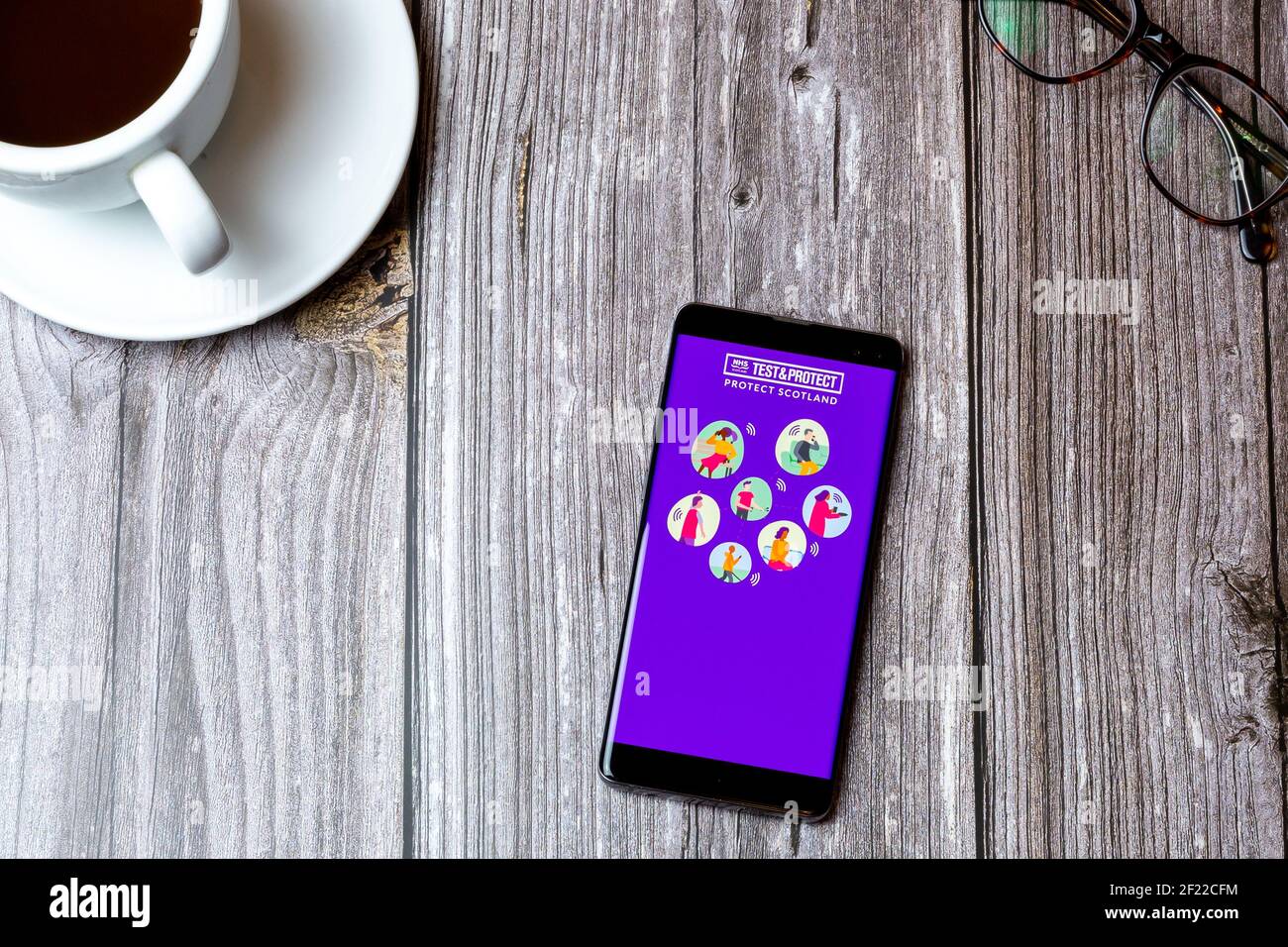 Un téléphone portable ou mobile posé sur un bois Table avec l'application test and Protect Scotland ouverte écran Banque D'Images