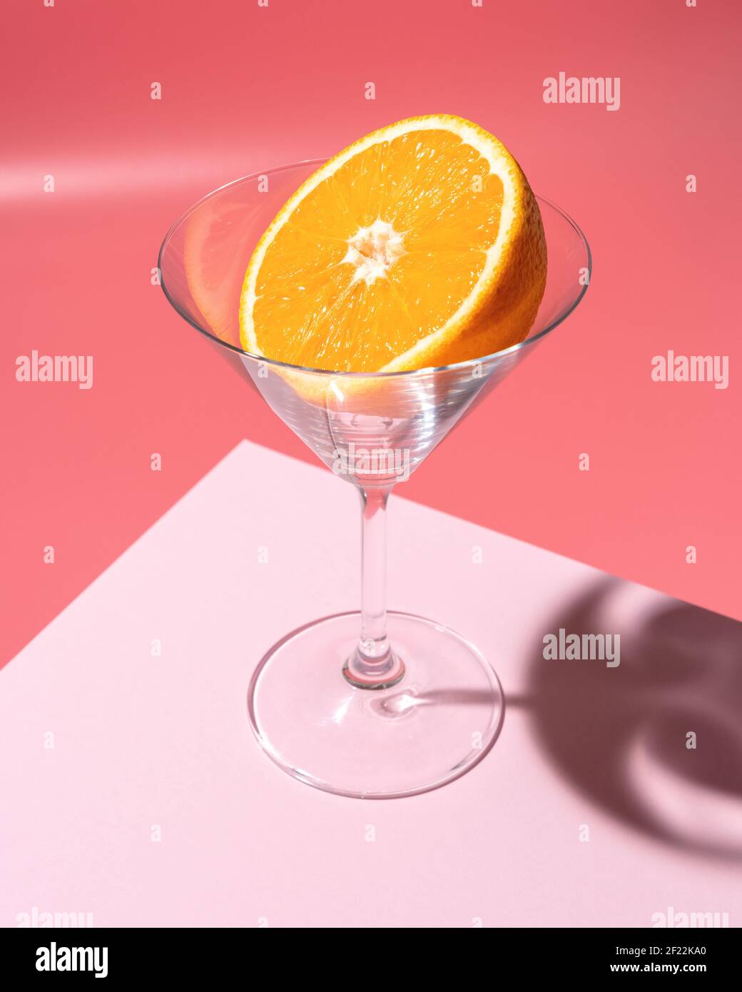 Fruit orange en verre martini sur fond clair. Concept de boisson minimale. Banque D'Images