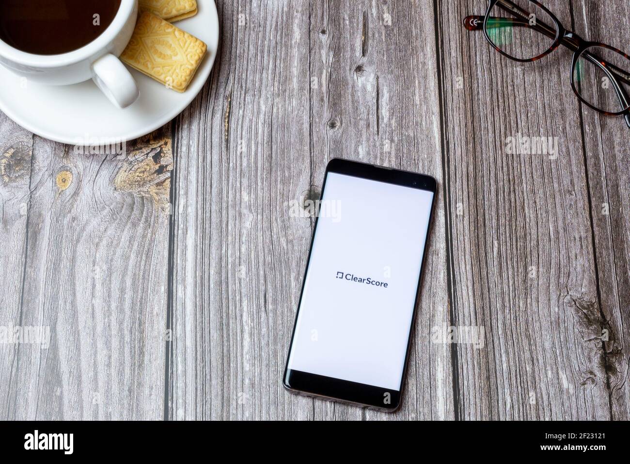 Un téléphone portable ou un téléphone portable sur une table en bois Avec l'application Clear score ouverte à côté d'un café et lunettes Banque D'Images