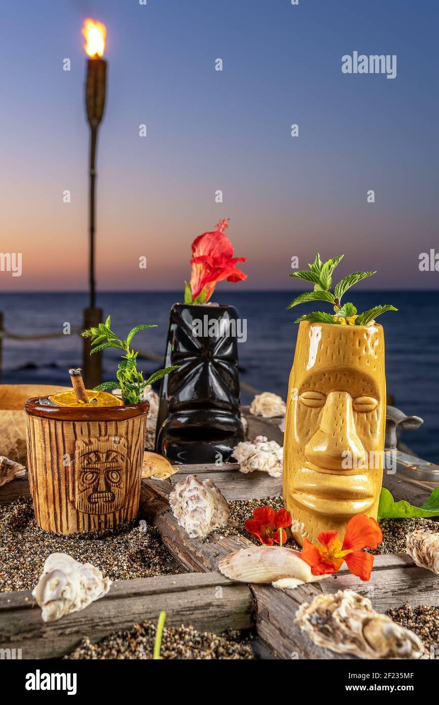 Différents cocktails de Tiki tropicaux sur le fond de la mer pendant le coucher du soleil. Banque D'Images