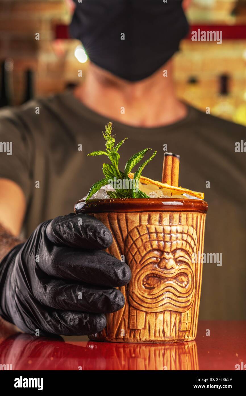 Barman donnant un cocktail Tiki au bar. Arrière-plan de la fête d'été. Banque D'Images