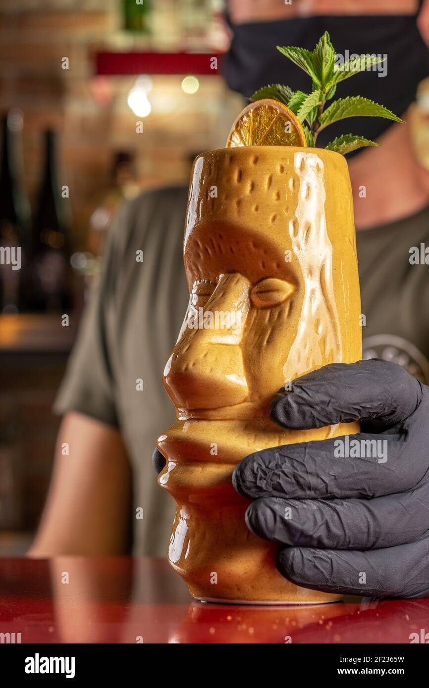 Barman donnant un cocktail Tiki au bar. Arrière-plan de la fête d'été. Banque D'Images
